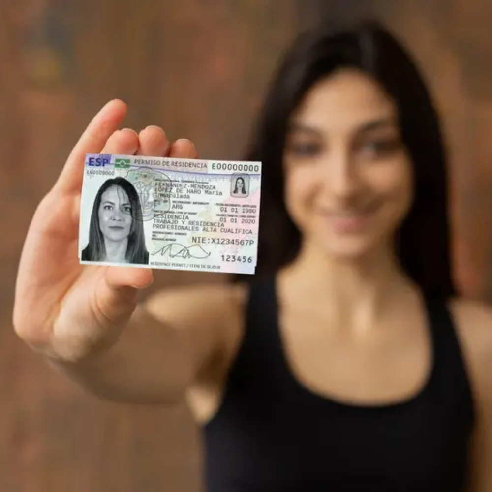 AbraCasaBra.se En kvinna i svart linne håller upp ett spanskt ID-kort för uppehållstillstånd mot kameran, med kortet i fokus och hennes ansikte suddigt i bakgrunden.