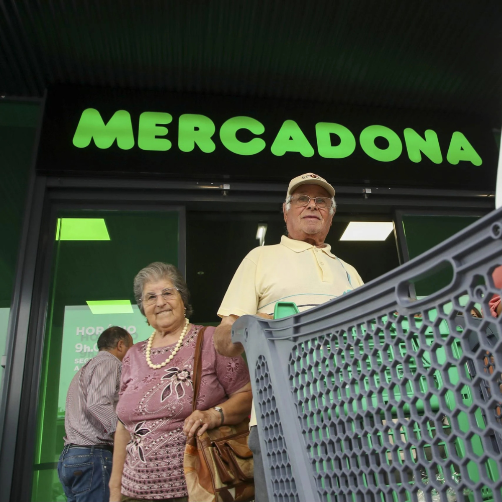 AbraCasaBra.se Ett äldre par står med en kundvagn utanför en Mercadona-stormarknad, med butikens gröna skylt synlig ovanför dem. I bakgrunden ses en annan person gå in i butiken.